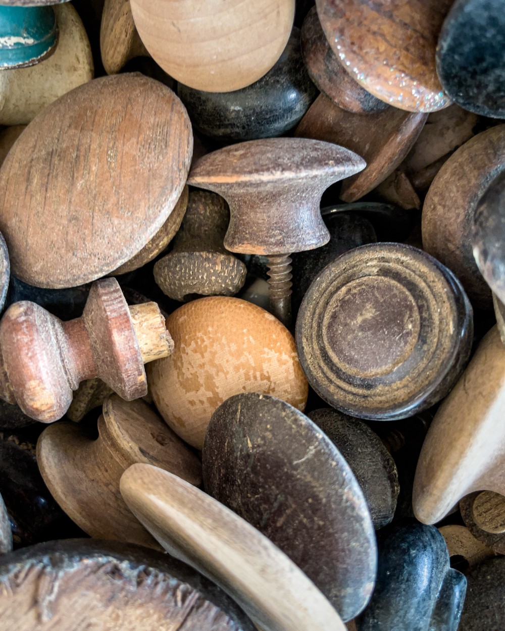 A close up photo of a collection of weathered wooden knobs.