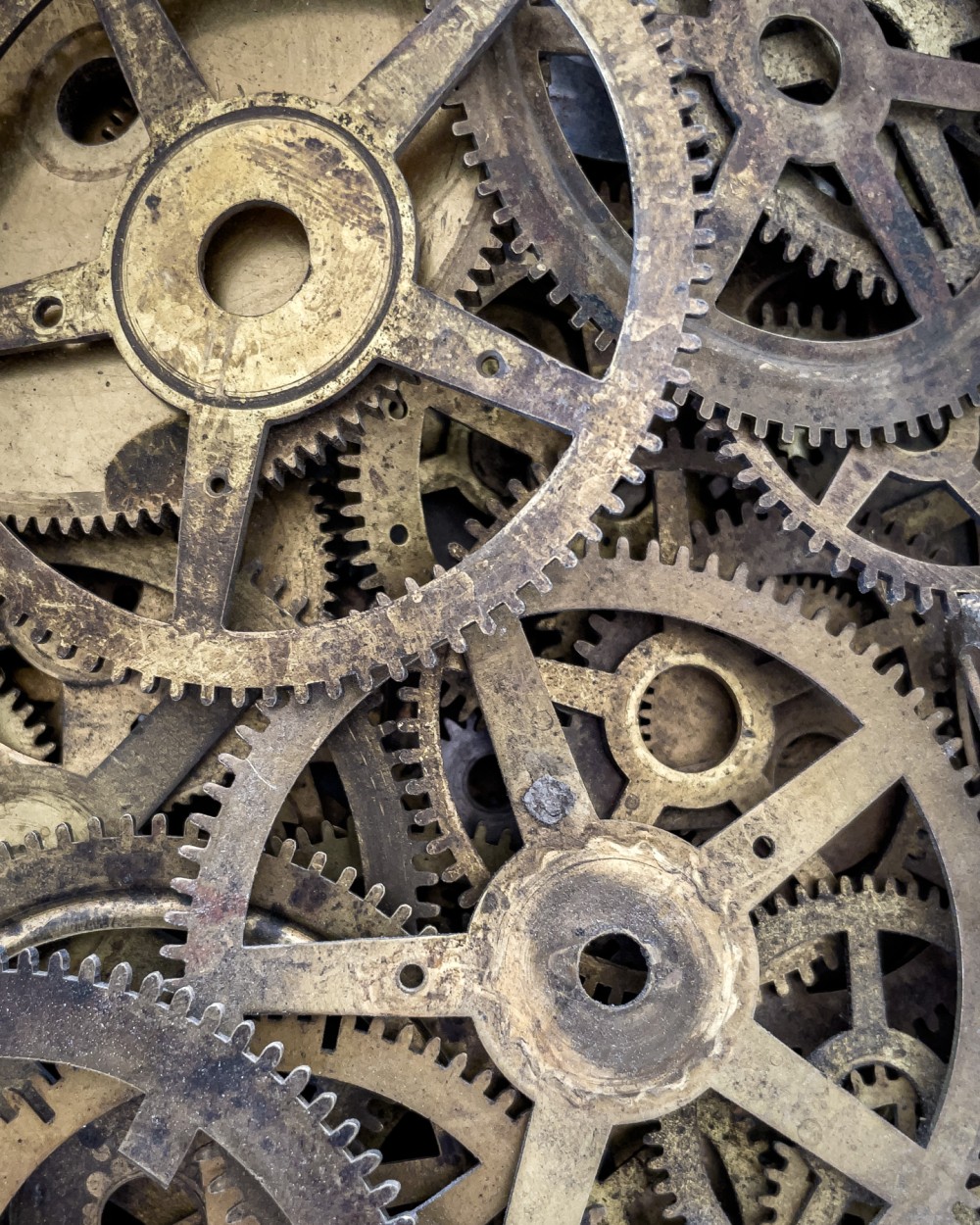 A close-up photo of a pile of weathered metal gears with intricate teeth.
