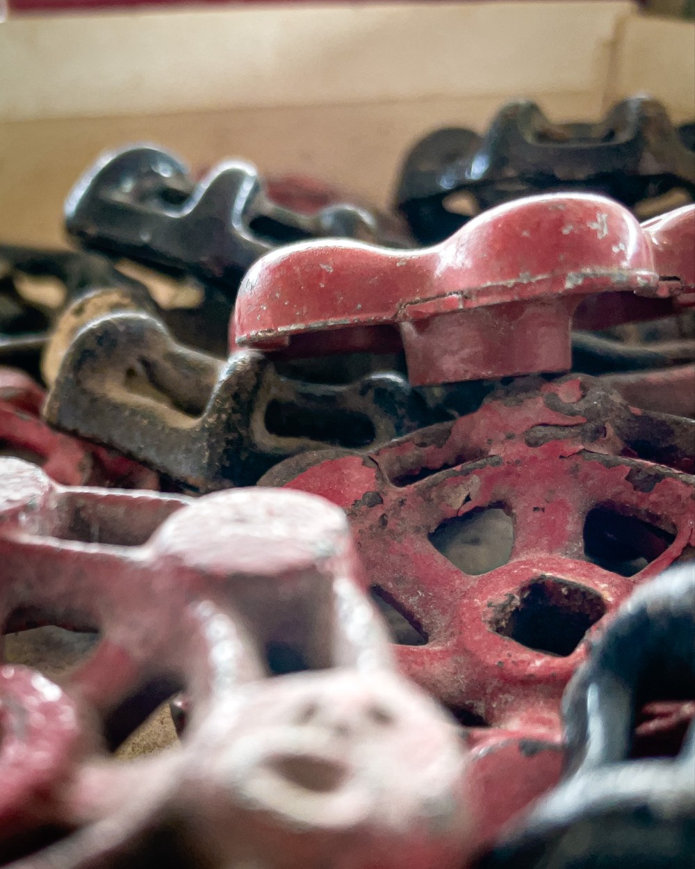 A close-up of a collection of old, rusted metal knobs with chipped red paint.