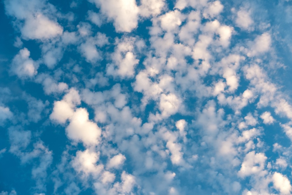 Scattered fluffy white clouds against a bright blue sky during golden hour