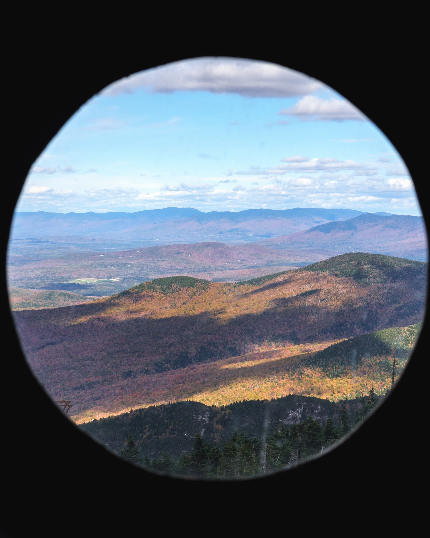 A scenic view of a mountainous landscape with colorful foliage seen through a circular frame.